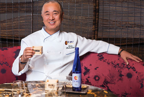 Chef Nobu sitting a table with glass of wine